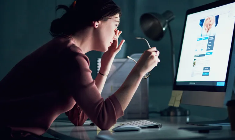 Shot of a young businesswoman using a computer during a late night at work and looking tired